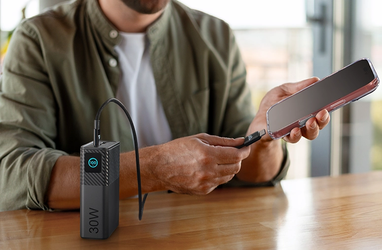 A man connects his smartphone to a Black Rock Power Pack via a cable.
